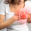 Mujer joven con las manos en el pecho simulando un infarto