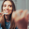 Mujer quitándose el retenedor de los dientes en el espejo del baño