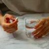 Manos femeninas con pastilla y vaso de agua