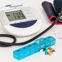 Aparato para medir la presión arterial junto a una caja con pastillas y cápsulas