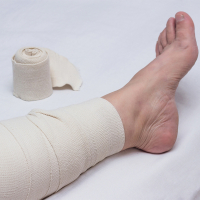 Pierna de una anciana vendada con vendaje elástico contra venas varicosas en la pierna