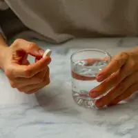 Manos femeninas con pastilla y vaso de agua