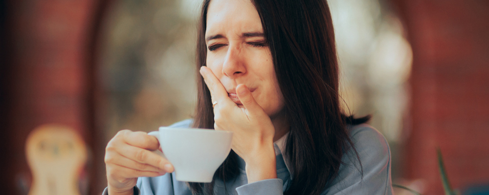 Mujer con sensibilidad dental bebiendo de una taza 