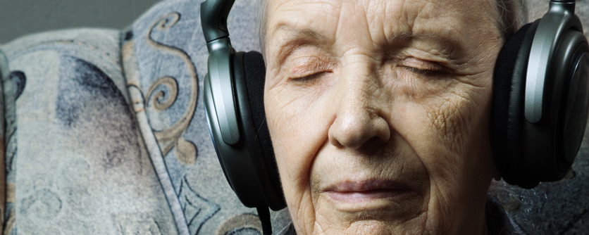 Hombre mayor escuchando música en un sillón con los ojos cerrados